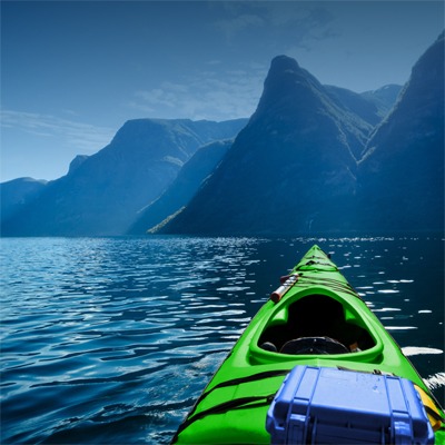 green-canoe-on-water-toward-bluish-mountains