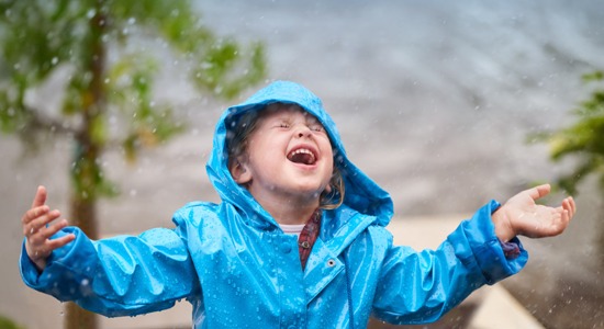 child-in-blue-raincoat-catching-rain-in-mouth